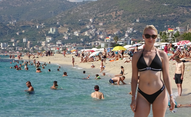 Alanya'da güneşli hava fırsat bilen tatilciler soluğu plajda aldı